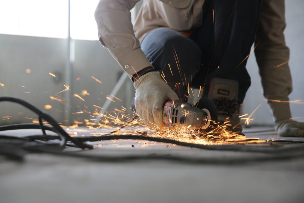 a man cutting metal with golden sparkles flying around from the cut